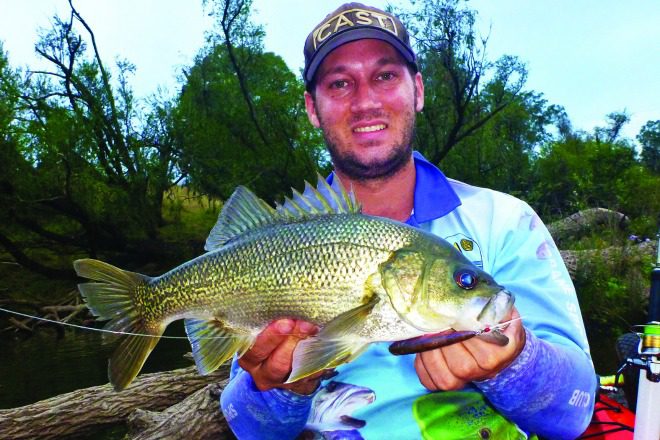 The author with a topwater bass hooked while slowly working a river.